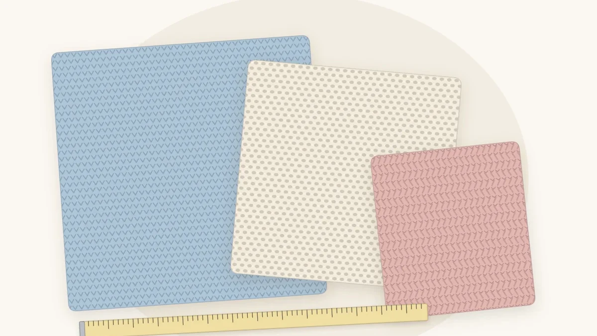 Three crocheted baby blankets of different sizes laid flat and overlapping, in pale blue, cream and dusty rose, with a tape measure