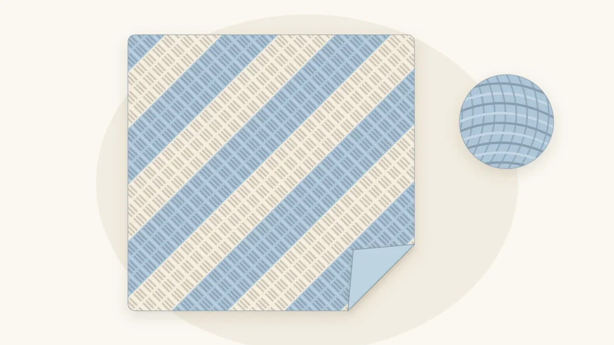 A corner-to-corner crochet baby blanket with diagonal rows of small blocks in pale blue and cream, one corner turned up