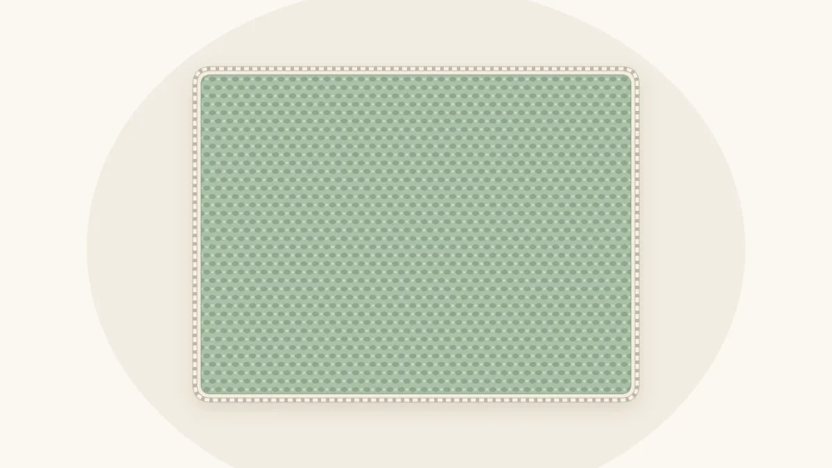 A sage green crochet baby blanket with a twisted rope-like corded edge in cream running along its border