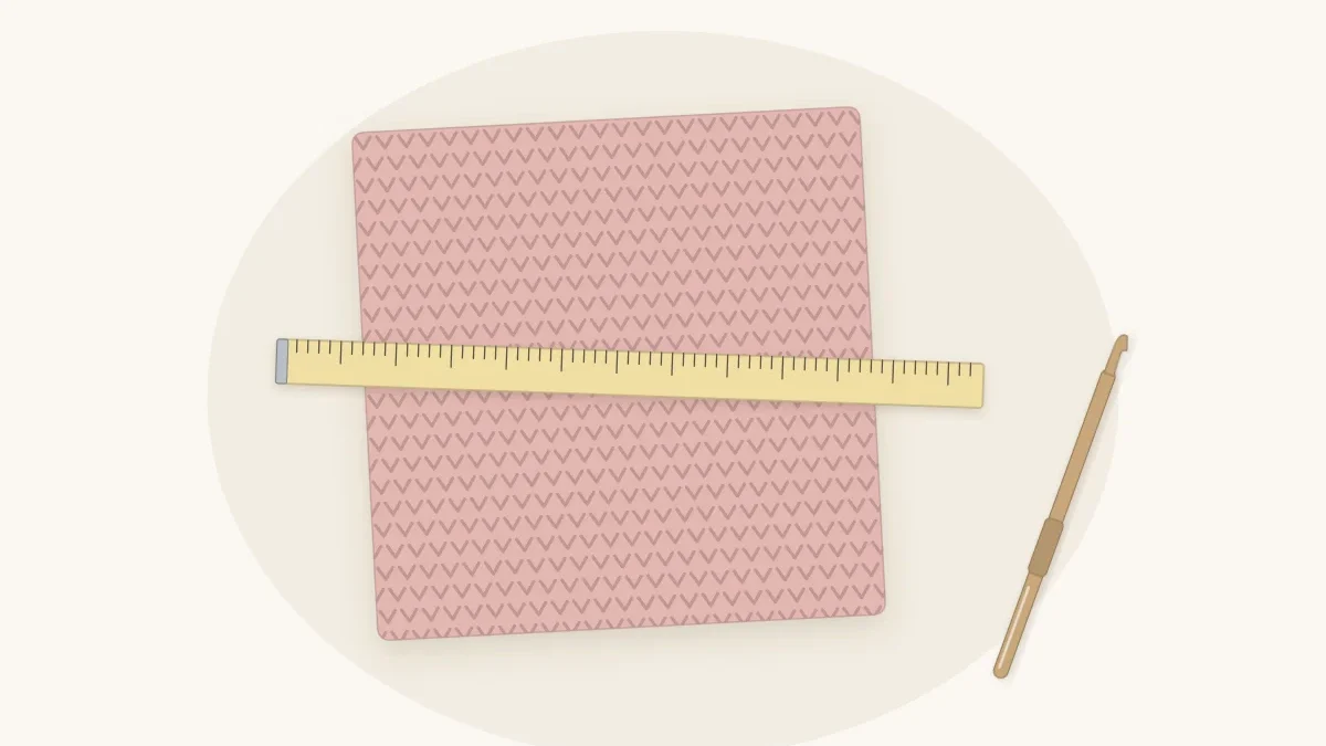 A square crochet gauge swatch in dusty rose with a tape measure laid across it and a crochet hook alongside