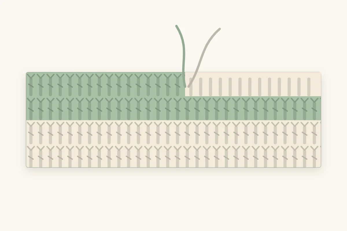 A row of crochet stitches changing from one color to another, with the two yarn tails hanging at the change point
