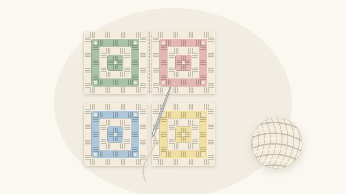 Four granny squares in soft colors laid out two by two with a yarn needle and cream yarn joining the first seam