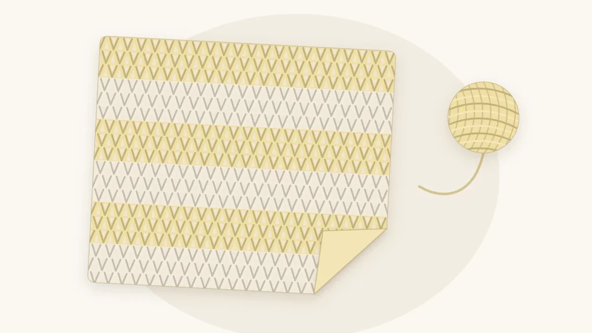 A light open-textured V-stitch crochet baby blanket in butter yellow and cream draped softly with a small ball of cotton yarn
