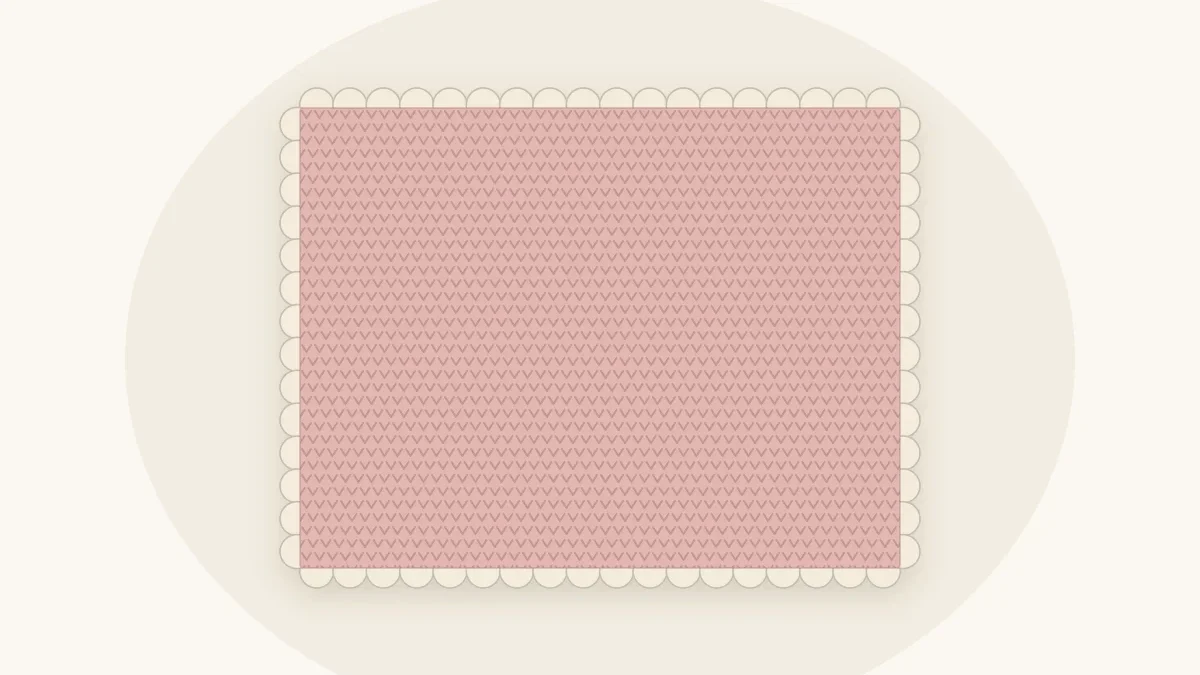 A dusty rose crochet baby blanket edged with a row of small rounded scallops in cream along its border