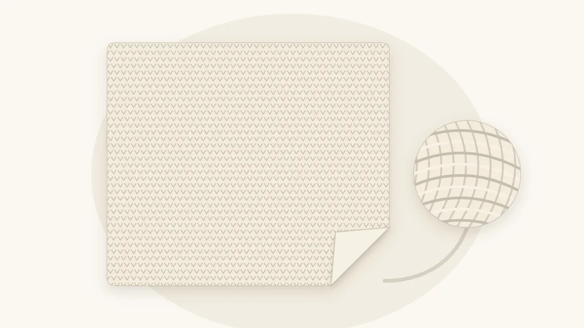 A cream single crochet baby blanket with a tight even texture, one corner folded back, next to a ball of cream yarn