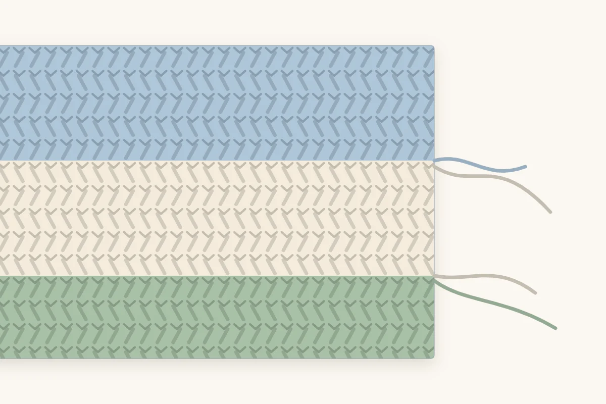 Close-up of the edge of a striped crochet blanket where one color row ends and the next color begins
